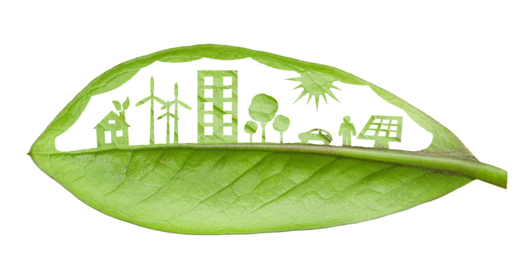 Green leaf cut in a way that shows a neighbourhood and various renewable energy sources