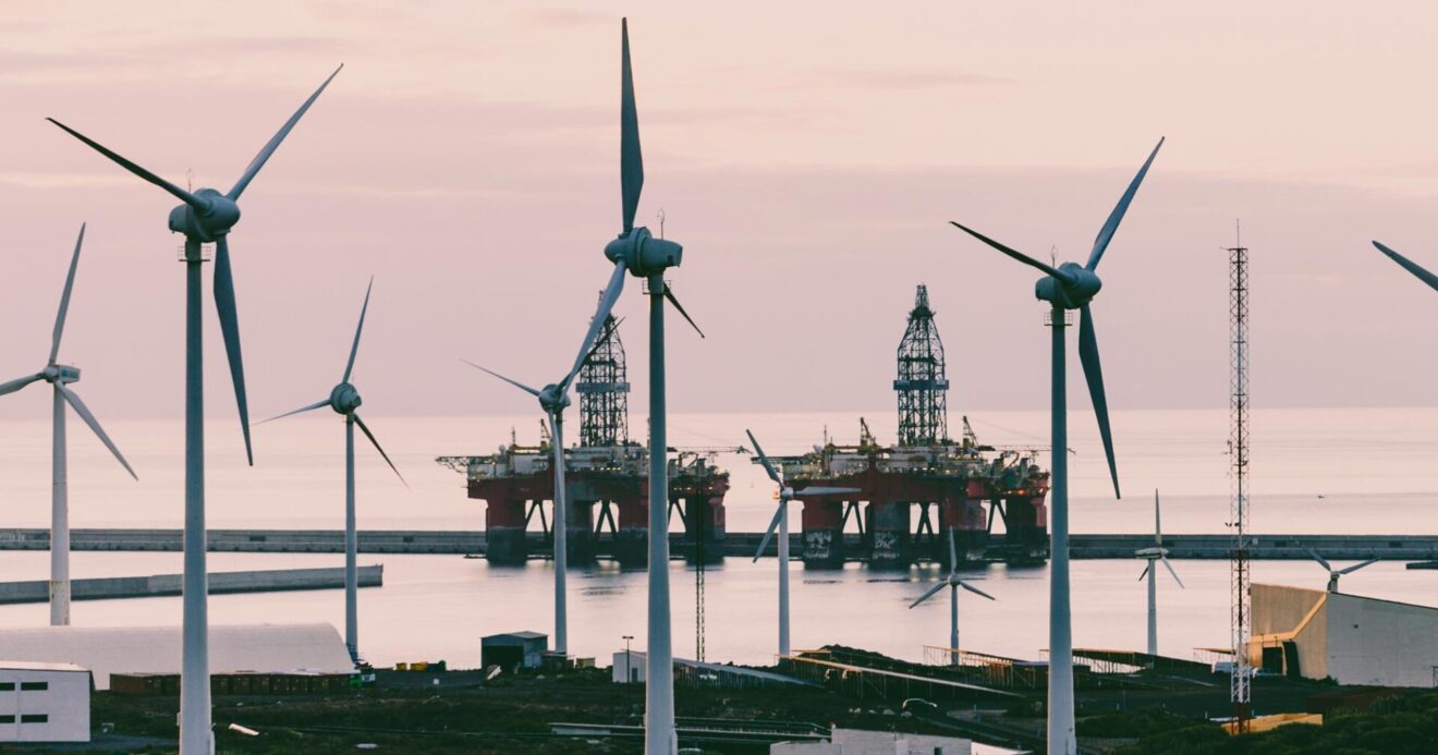 Wind turbines in the foreground, with oil platforms in the background.