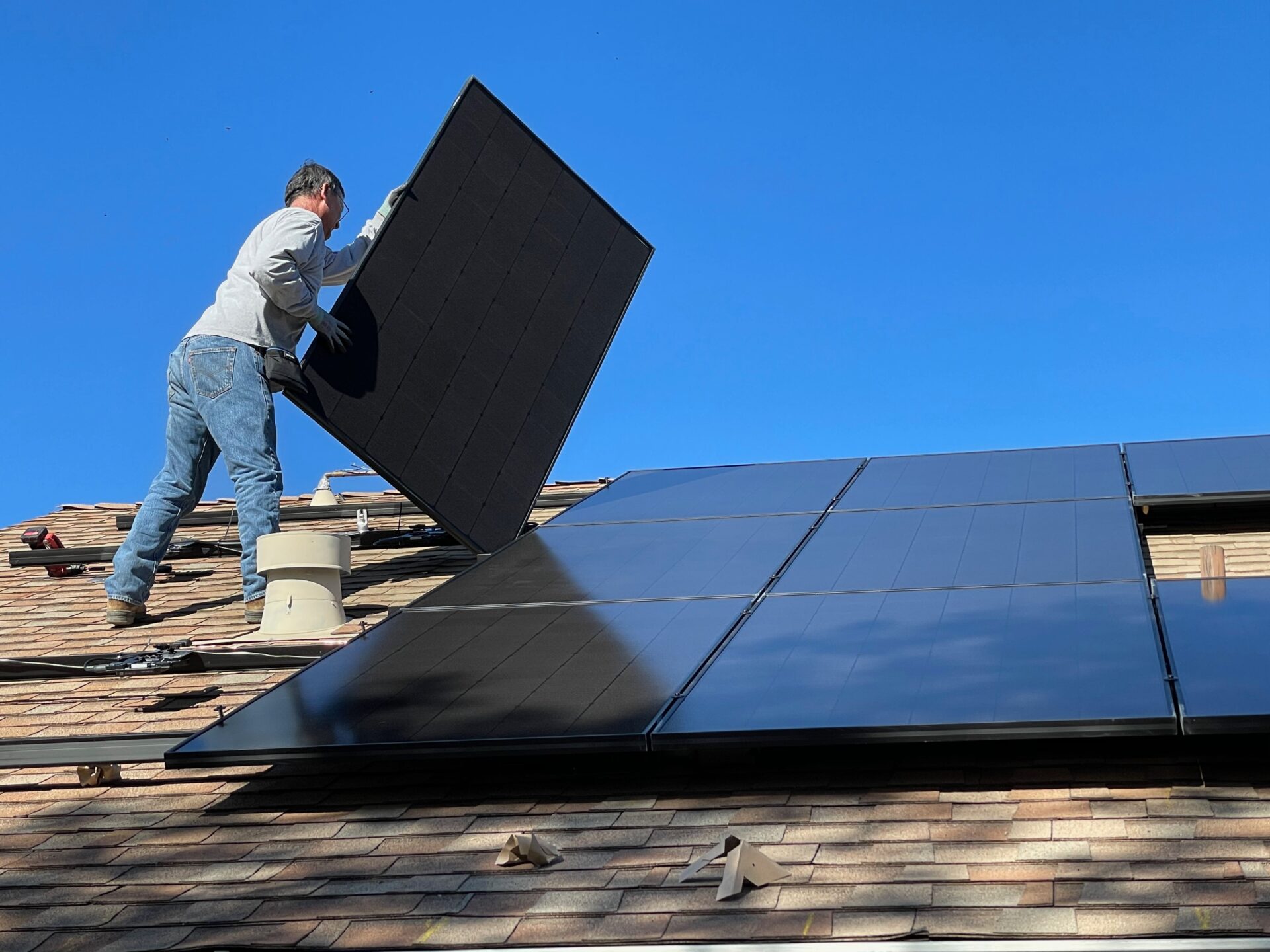 Mann monterer solcellepaneler på taket