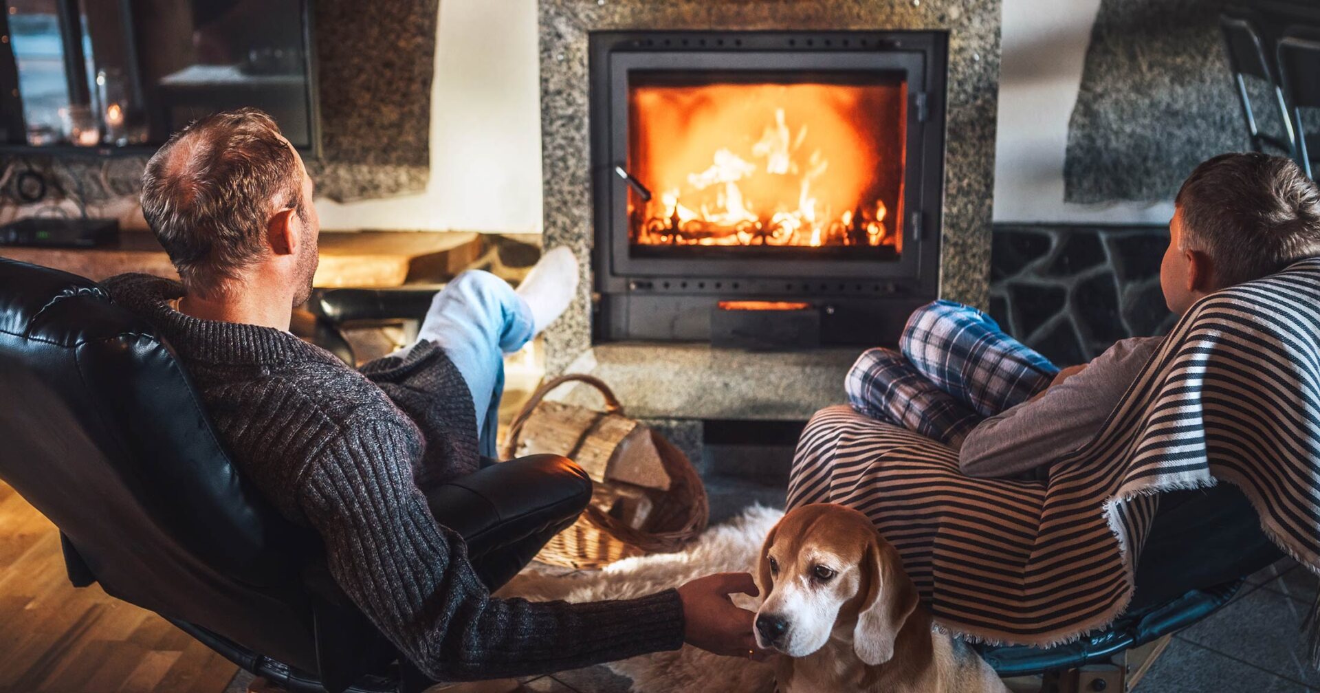 A father and son relax in front of a wood burning stove.