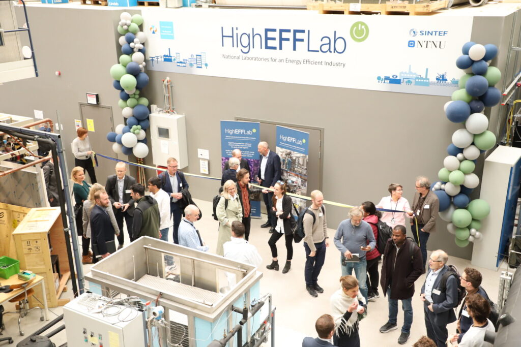 Official opening of HighEFFLab. Picture taken from above, showing banner, people people eating cake and lab equipment.