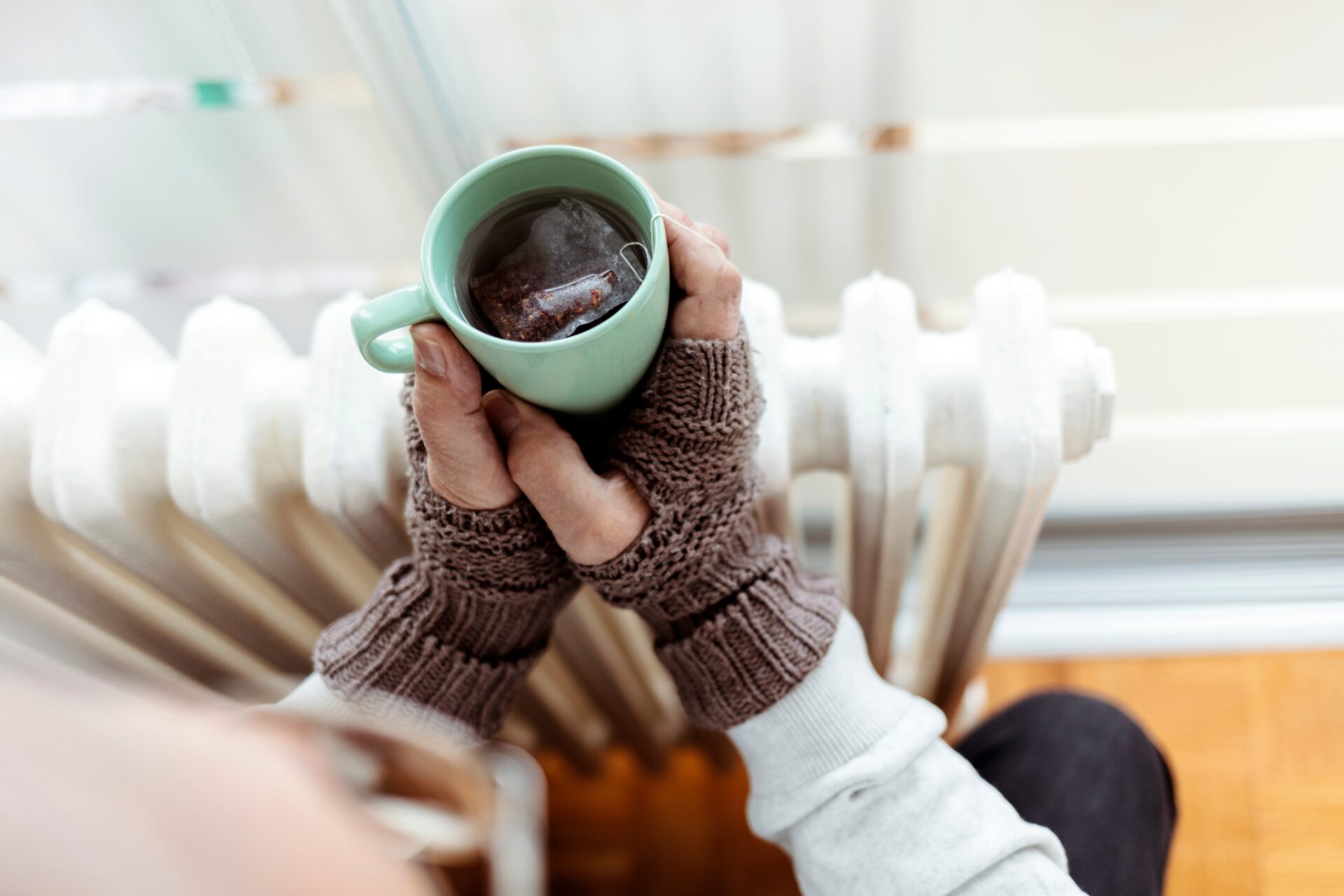 energikrise en person som holder en tekopp foran en radiator