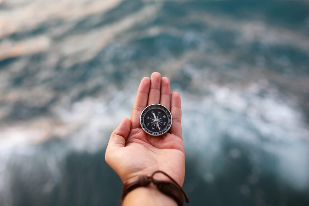 man holding compass over waves