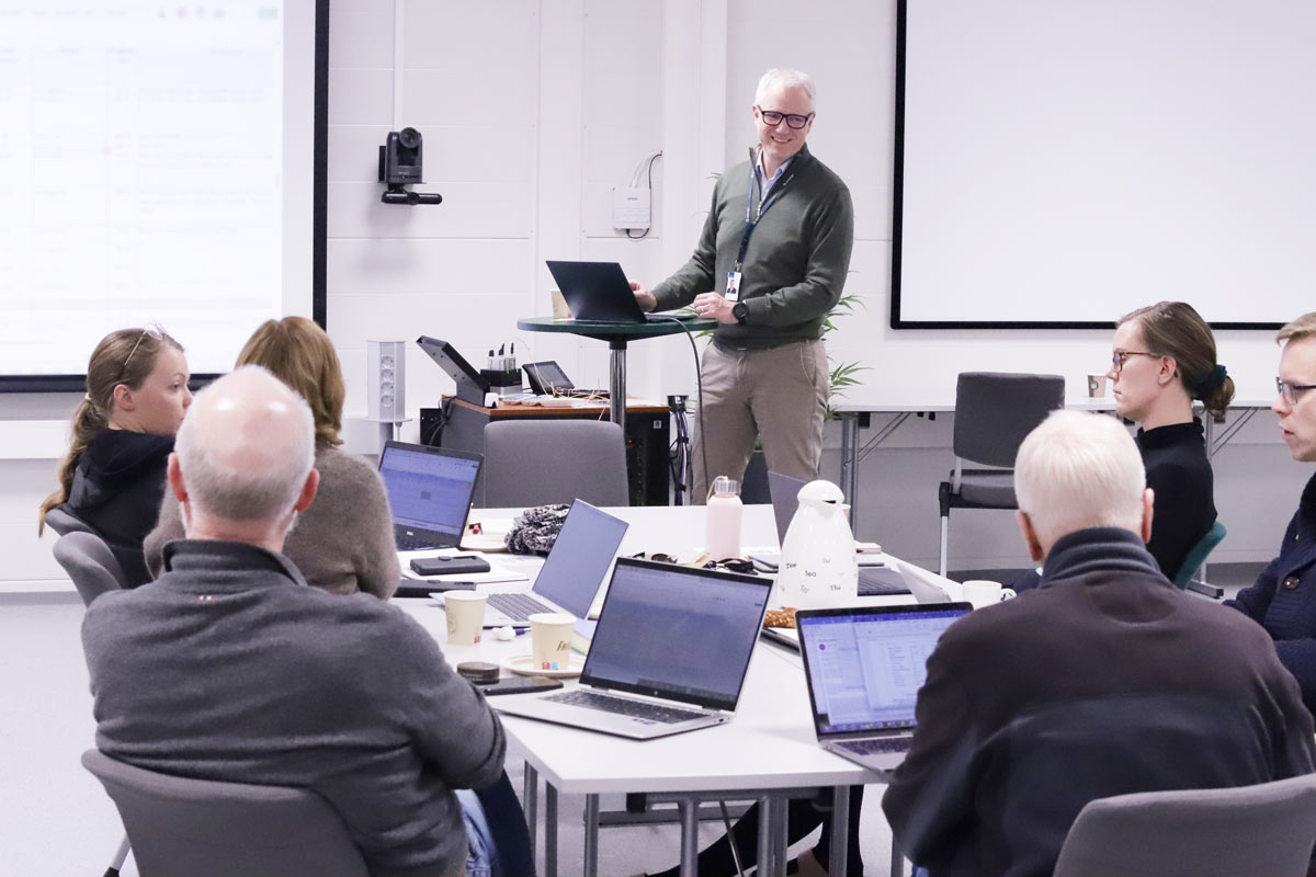 FME HighEFF director Petter Røkke stands at a small podium with a laptop, leading a meeting of the Centre's management team.